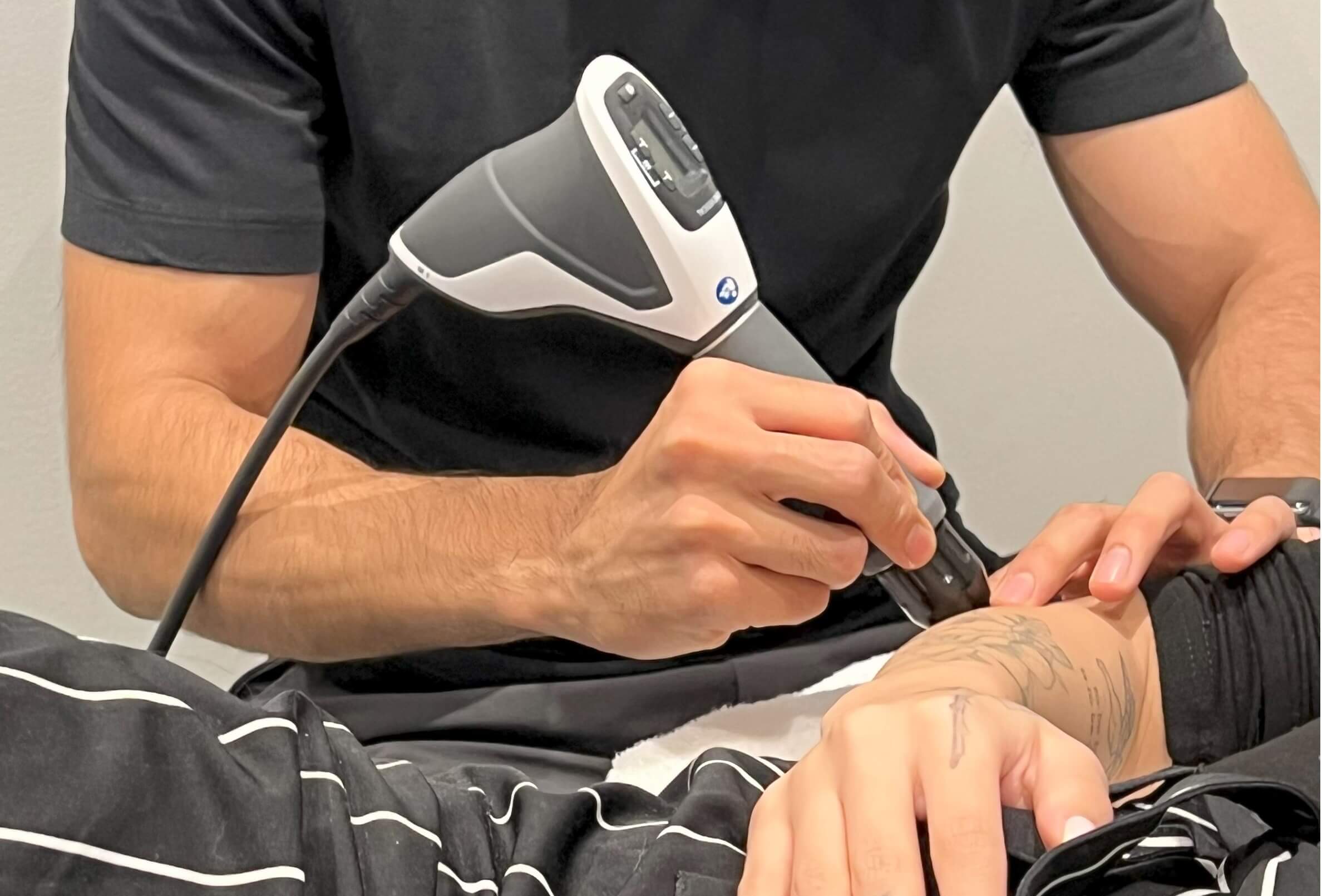 A man performs shockwave therapy on a patient.